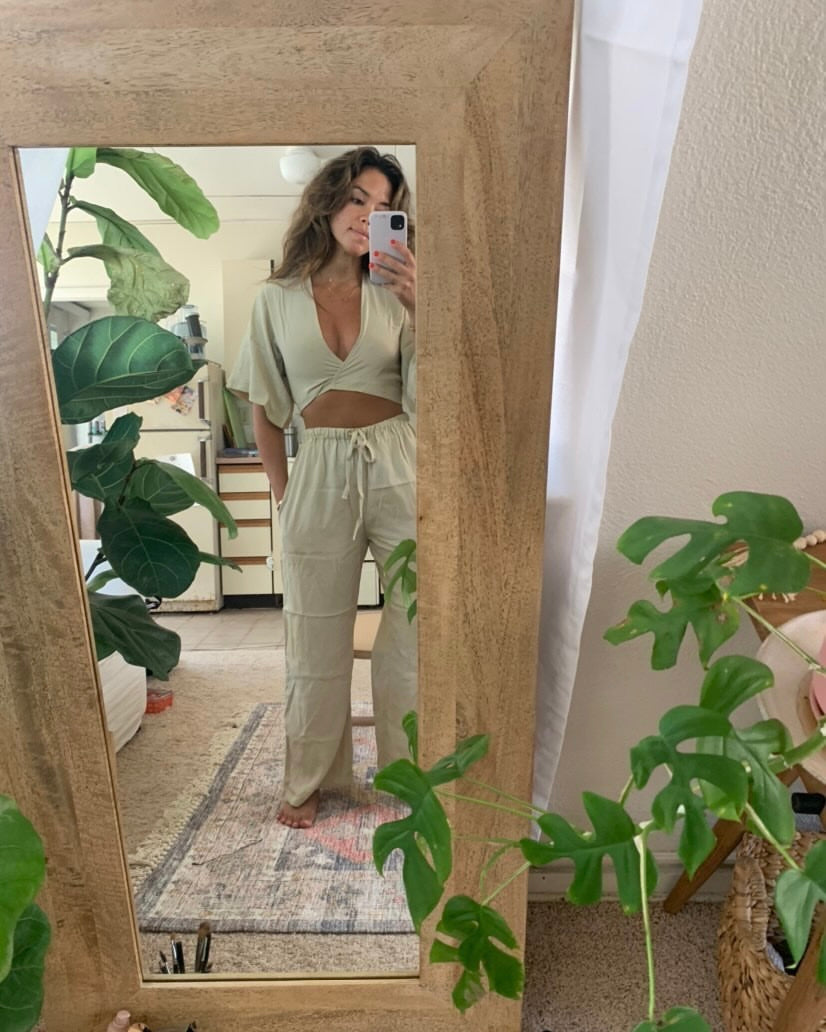 Mirror selfie of girl wearing white monochrome set in her lounge with plants.