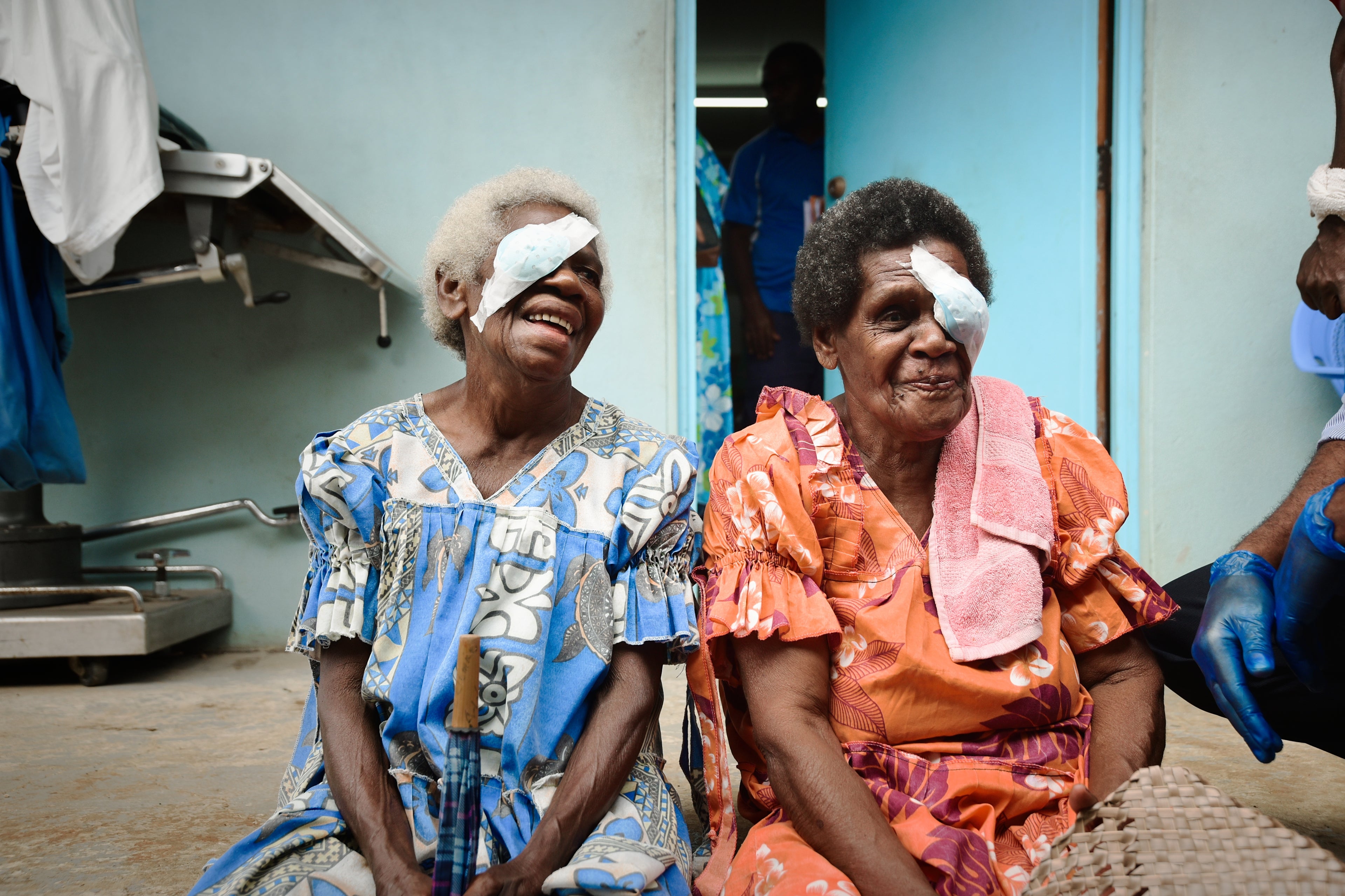 Two Pacific Island women with eye patch, smiling after restoring eyesight.